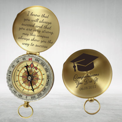 May include: A gold compass with a graduation cap design and the text "Congratulations You Did It 06.08.2022". The compass has a message on the back that reads "I know that you will always succeed and that you are very strong. May this compass always show you the way to success."