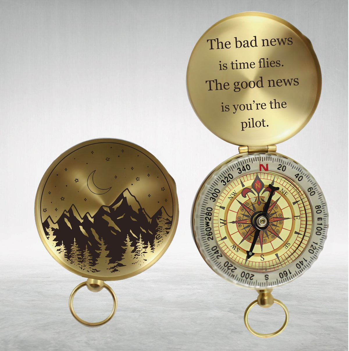 May include: A gold compass with a mountain and moon design on the lid. The compass face has a traditional design with north, south, east, and west markings. The lid reads "The bad news is time flies. The good news is you're the pilot."