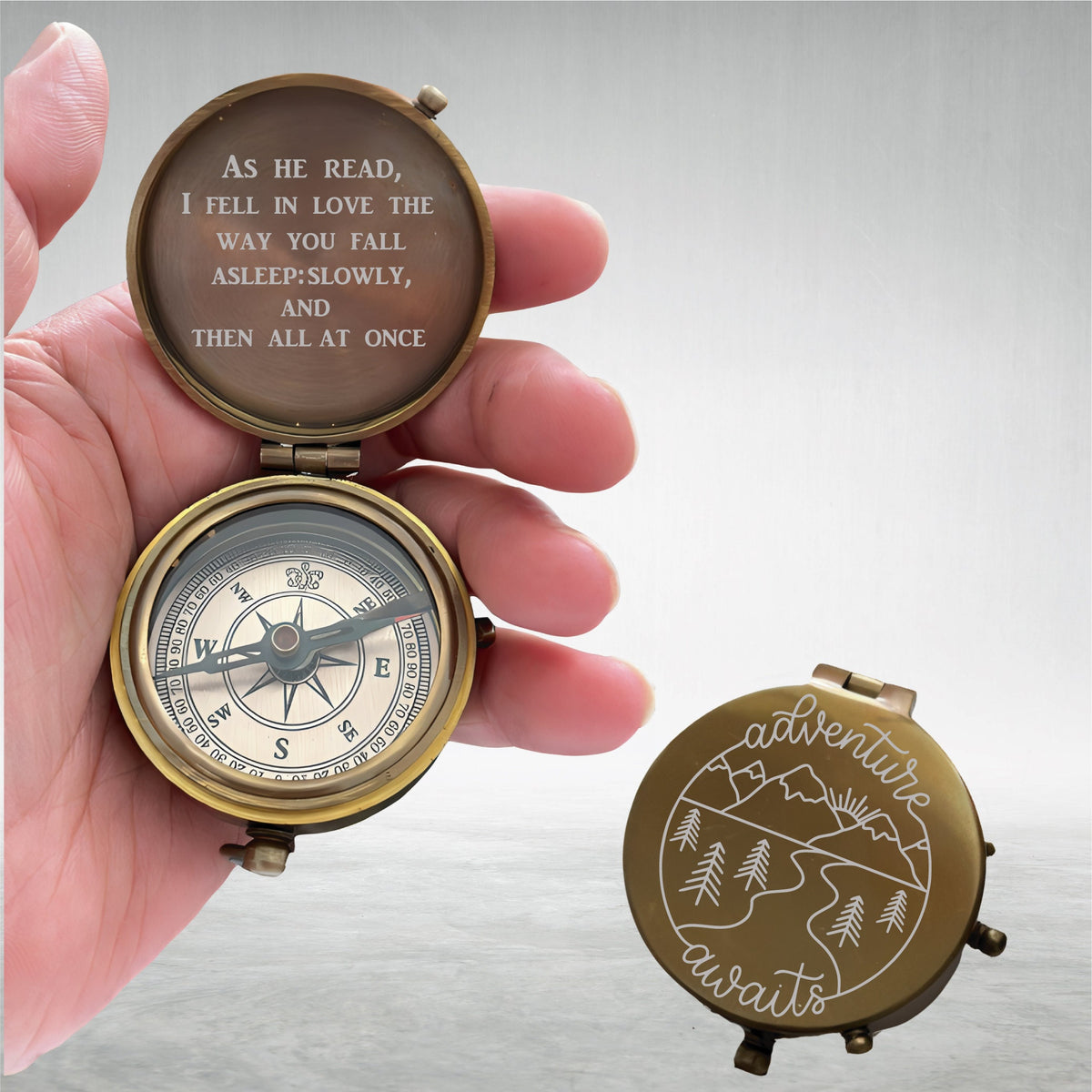 May include: A brass compass with a quote engraved on the lid: "As he read, I fell in love the way you fall asleep: slowly, and then all at once". The compass is open and the needle is pointing north. The other side of the compass has a mountain scene with the words "adventure awaits" engraved on it.
