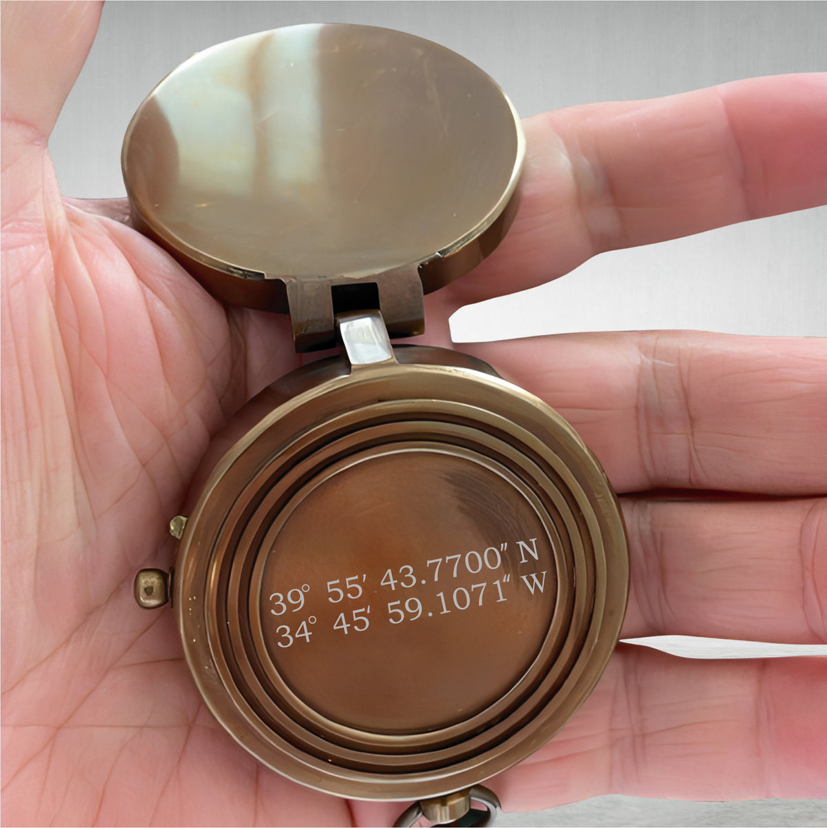 May include: A brass compass with a hinged lid. The compass face has engraved coordinates: 39° 55' 43.7700" N 34° 45' 59.1071" W.