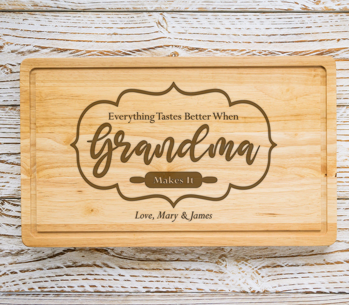 May include: A wooden cutting board with the text "Everything Tastes Better When Grandma Makes It" in a brown font. The text is surrounded by a decorative frame. The bottom of the board has the text "Love, Mary & James".