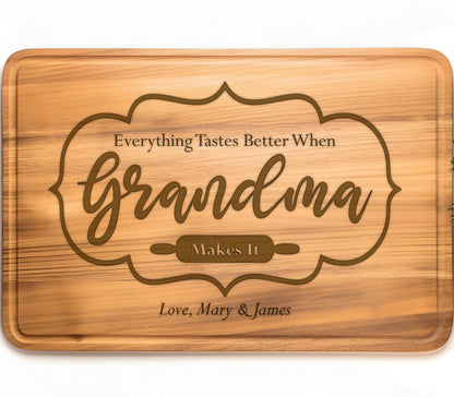 May include: A wooden cutting board with an engraved message that reads "Everything Tastes Better When Grandma Makes It". The message is surrounded by a decorative frame. The board is signed "Love, Mary & James".