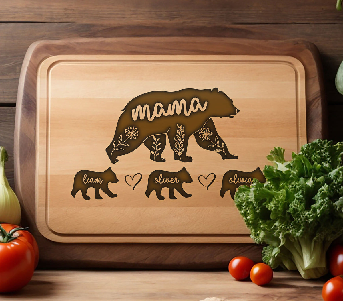 May include: Wooden cutting board with a bear design. The word "mama" is inside the bear silhouette, with floral accents. Below are bear cub silhouettes with names "Liam", "Oliver", and "Olivia". A heart symbol is between "Liam" and "Oliver".
