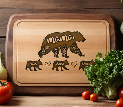 May include: Wooden cutting board with a bear design. The word "mama" is inside the bear silhouette, with floral accents. Below are bear cub silhouettes with names "Liam", "Oliver", and "Olivia". A heart symbol is between "Liam" and "Oliver".