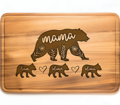 May include: A rectangular wooden cutting board with a bear design. The word "mama" is carved into the bear's body, with floral accents. Below are three smaller bear figures with the names "liam", "oliver", and "olivia".