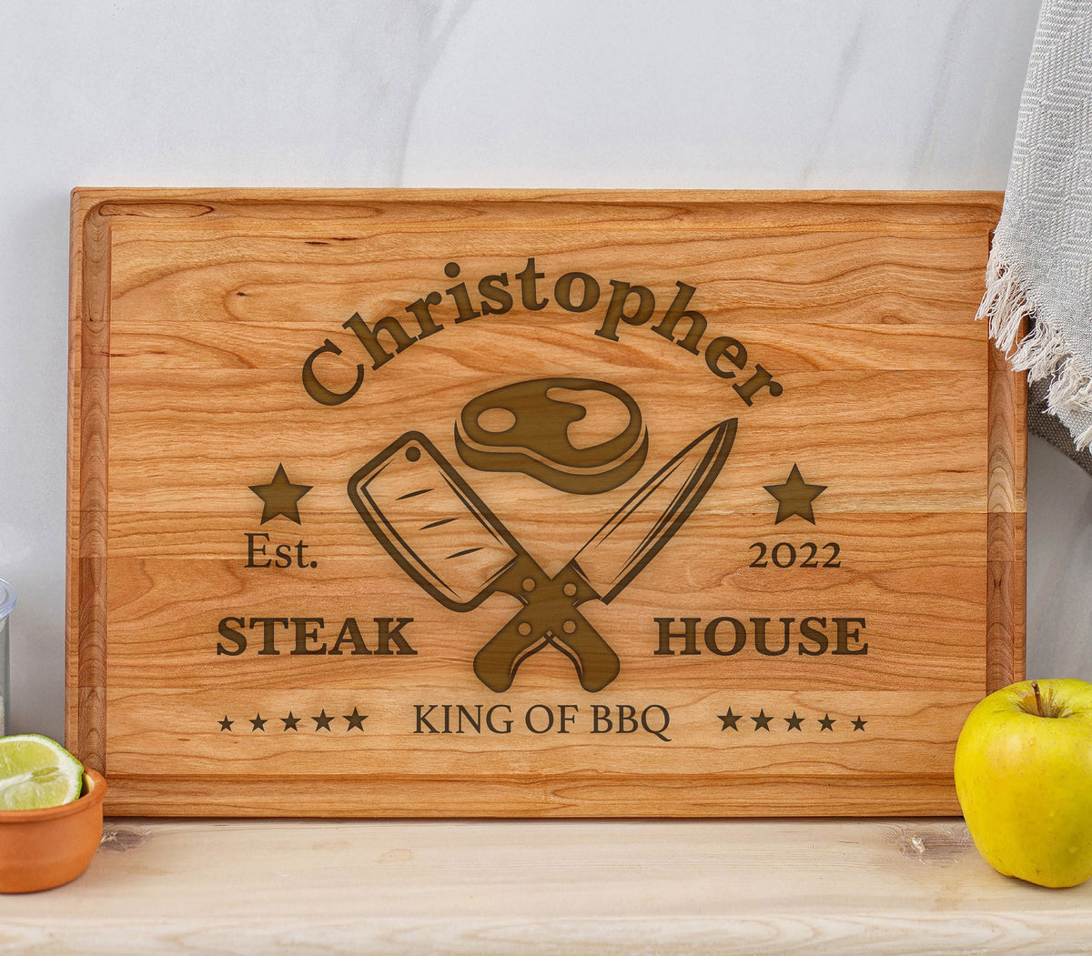 May include: A personalized wooden cutting board with the text "Christopher Steak House Est. 2022 King of BBQ" and a graphic of crossed knives and a steak.