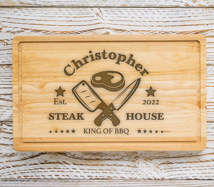 May include: A personalized wooden cutting board with the text "Christopher Steak House Est. 2022 King of BBQ" and a graphic of a steak and crossed knives.