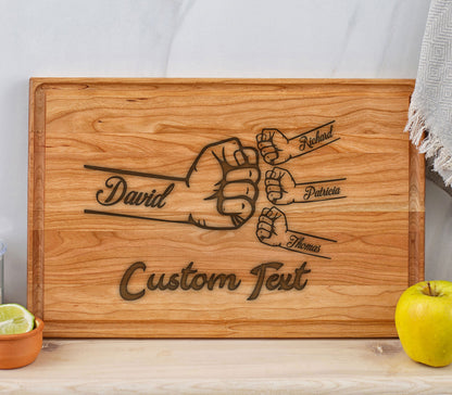 May include: A wooden cutting board with a design of five fists bumping each other. The names David, Richard, Patricia, and Thomas are engraved on the fists. The text "Custom Text" is also engraved on the board.