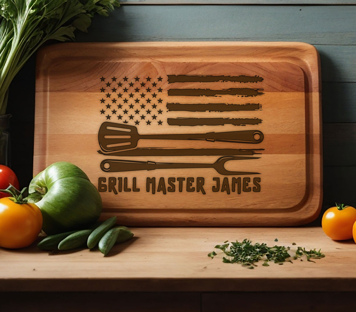 May include: A wooden cutting board with an American flag design and the text "Grill Master James". The flag is brown and the text is in a brown font. There are three grilling tools on the board, a spatula, a knife, and a fork.
