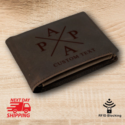 May include: Brown leather wallet with a cross design and the letters "APA" engraved on the front. The wallet also has the text "CUSTOM TEXT" engraved on the front.