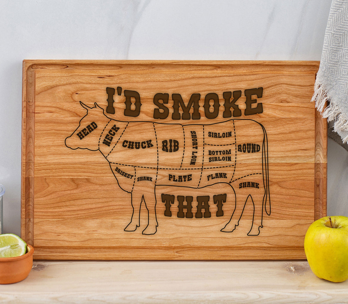 May include: A wooden cutting board with a cow silhouette and the text "I'D SMOKE THAT". The cow is divided into different cuts of meat, including head, neck, chuck, rib, short loin, sirloin, bottom sirloin, round, brisket, shank, plate, flank, and shank.