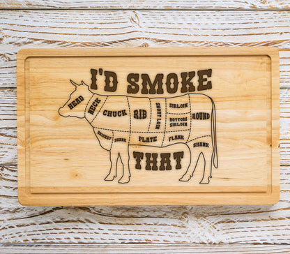 May include: A wooden cutting board with a silhouette of a cow and the text "I'D SMOKE THAT". The cow is divided into different cuts of meat, including chuck, rib, short loin, sirloin, bottom sirloin, round, flank, brisket, shank, and plate.