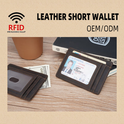 May include: A brown leather short wallet with RFID blocking technology. The wallet has two card slots and a clear ID window. The wallet is on a wooden surface with a dollar bill and a book.