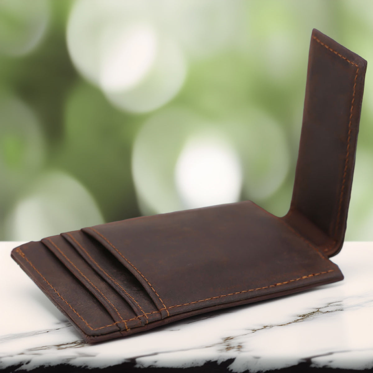 May include: A brown leather wallet with visible card slots and orange stitching. The wallet is open, displaying its interior and the texture of the leather. The background is blurred, with a marble surface.