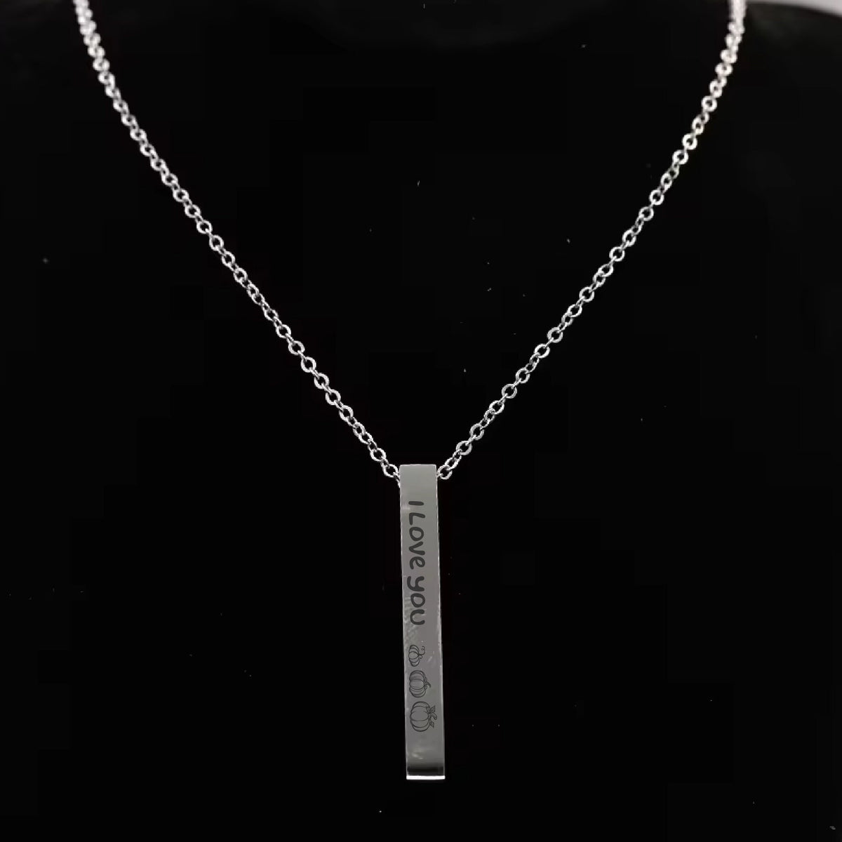 May include: A silver necklace with a vertical bar pendant that reads "I Love You" with a heart and three pumpkins engraved on it.