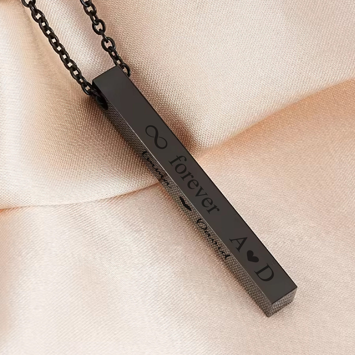 May include: A black bar necklace with an infinity symbol, the words "forever yours", and the letters "A & D" with a heart symbol.