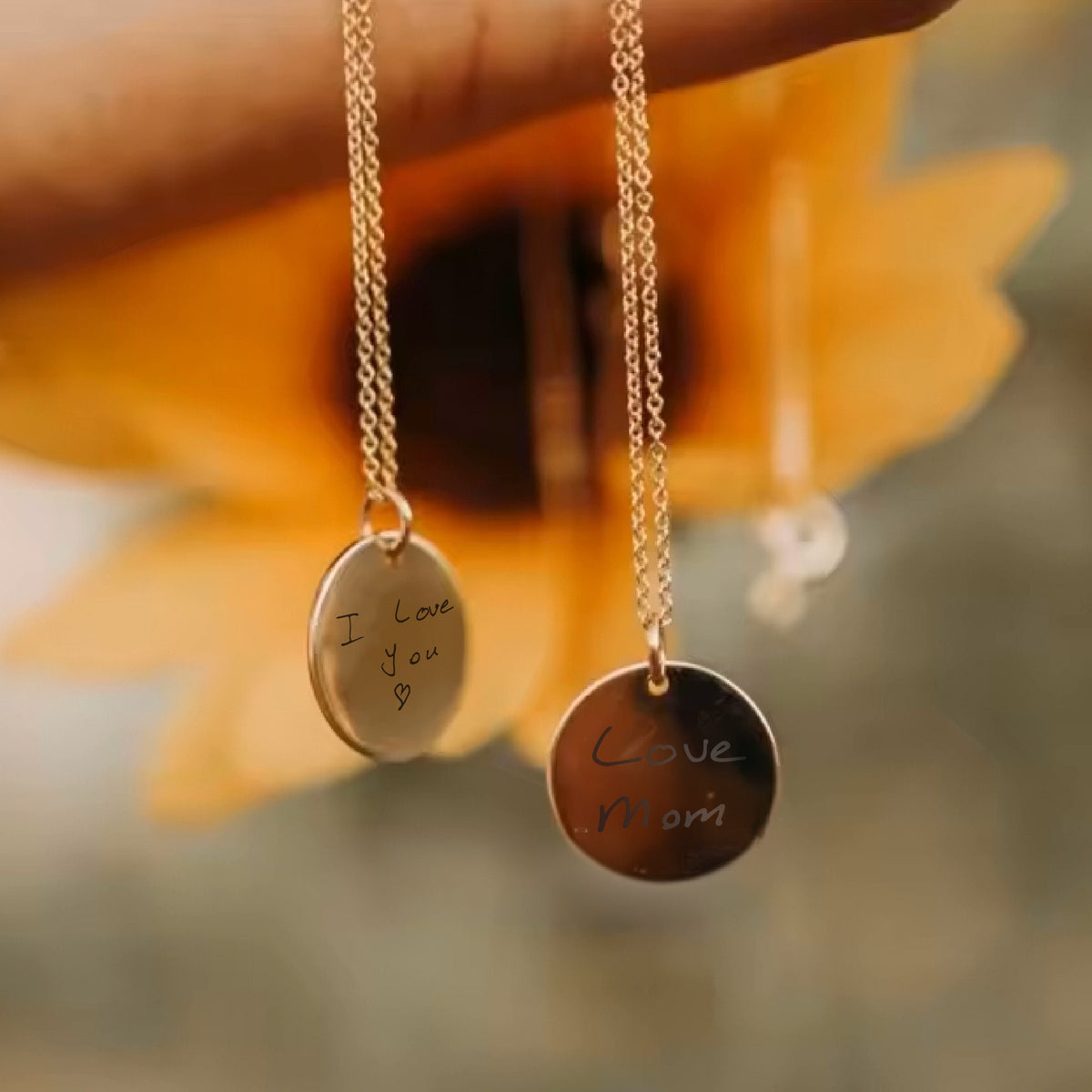 May include: Two gold necklaces with round pendants. The pendants have handwritten messages: "I love you" and "Love Mom".