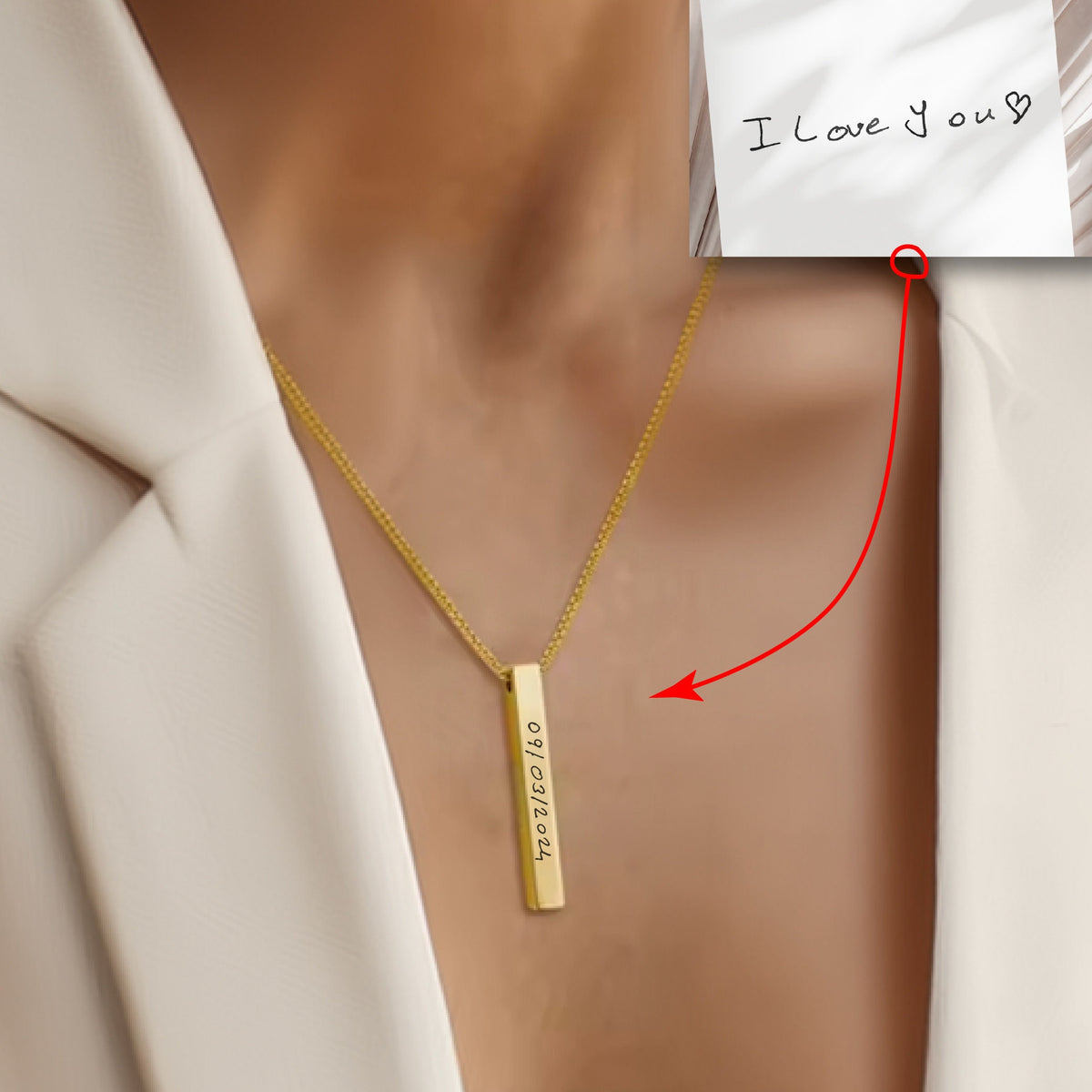 May include: A gold necklace with a vertical bar pendant engraved with the date "09/12/2024". The necklace is worn by a person with a white shirt. A handwritten note with the text "I love you" is visible in the background.