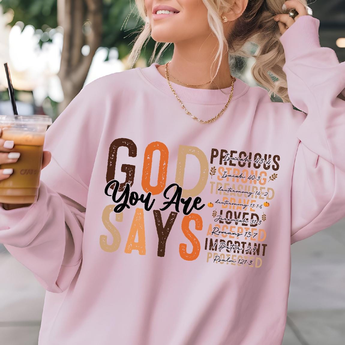 May include: Pink sweatshirt with a graphic print of the word "GOD" in large letters with the words "You Are" in smaller letters below. The graphic also includes the words "Precious", "Strong", "Treasures", "Loved", "Accepted", "Important", and "Protected" with bible verses listed next to each word.