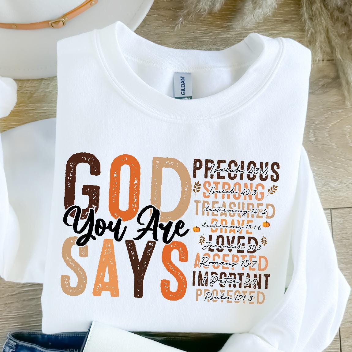 May include: White sweatshirt with the text "GOD You Are SAYS" in brown, orange, and beige lettering. The text is layered with scripture verses in smaller font.