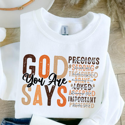 May include: White sweatshirt with the text "GOD You Are SAYS" in brown, orange, and beige lettering. The text is layered with scripture verses in smaller font.