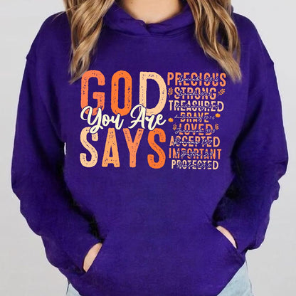 May include: Purple hoodie with a graphic print that says "God You Are Says" with a list of positive affirmations in orange and white text. The affirmations include "Precious", "Strong", "Treasured", "Brave", "Loved", "Accepted", "Important", and "Protected".