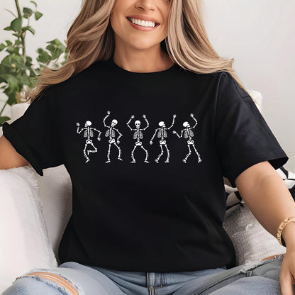 May include: Black t-shirt featuring a white graphic of five dancing skeletons. The skeletons are in various poses with their arms raised. The shirt is made of a soft material and has short sleeves. The overall theme is Halloween or a spooky celebration.