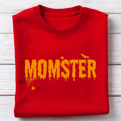 May include: A red sweatshirt with the word "MOMSTER" in orange dripping letters. The design includes a spider web, spiders, and a bat, all in orange. The sweatshirt is folded neatly on a white wooden surface.