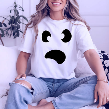 May include: White t-shirt featuring a black ghost face design. The graphic includes two curved eyes and a curved mouth, creating a surprised expression. The shirt is short-sleeved and appears to be made of a soft material.
