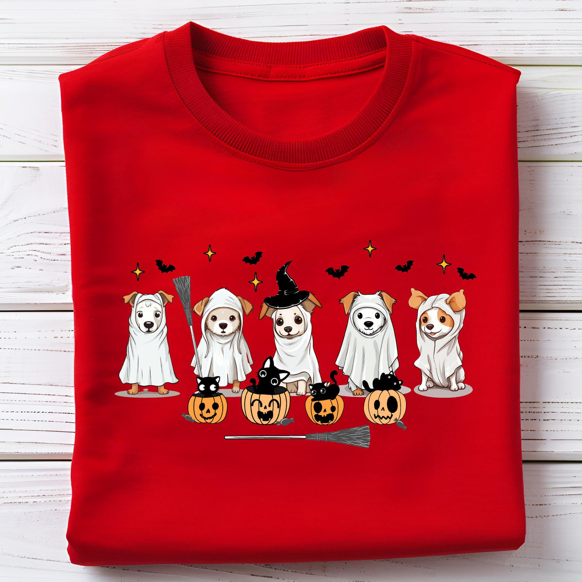 May include: A bright red t-shirt featuring a graphic print of five dogs dressed in white ghost costumes, with black cats sitting inside orange jack-o'-lanterns, surrounded by small black bats and yellow stars, with a broomstick illustration.