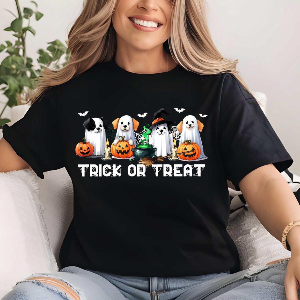 May include: A black t-shirt featuring a graphic of four dogs dressed as ghosts, surrounded by orange pumpkins, a green bubbling cauldron, lit candles, and small bats. The text "TRICK OR TREAT" is printed in white below the illustration.