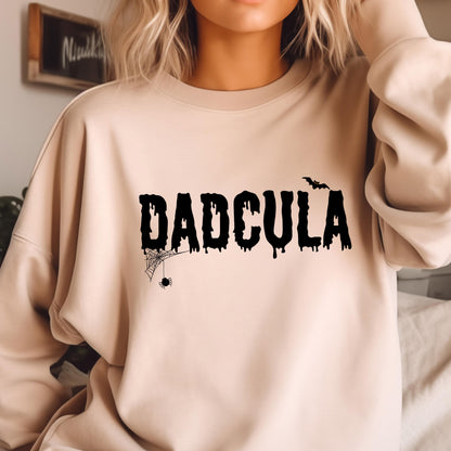 May include: A light beige sweatshirt with a black graphic print that says "DADCULA" with a dripping effect. A spider web and spider are below the text and a bat is above the text.