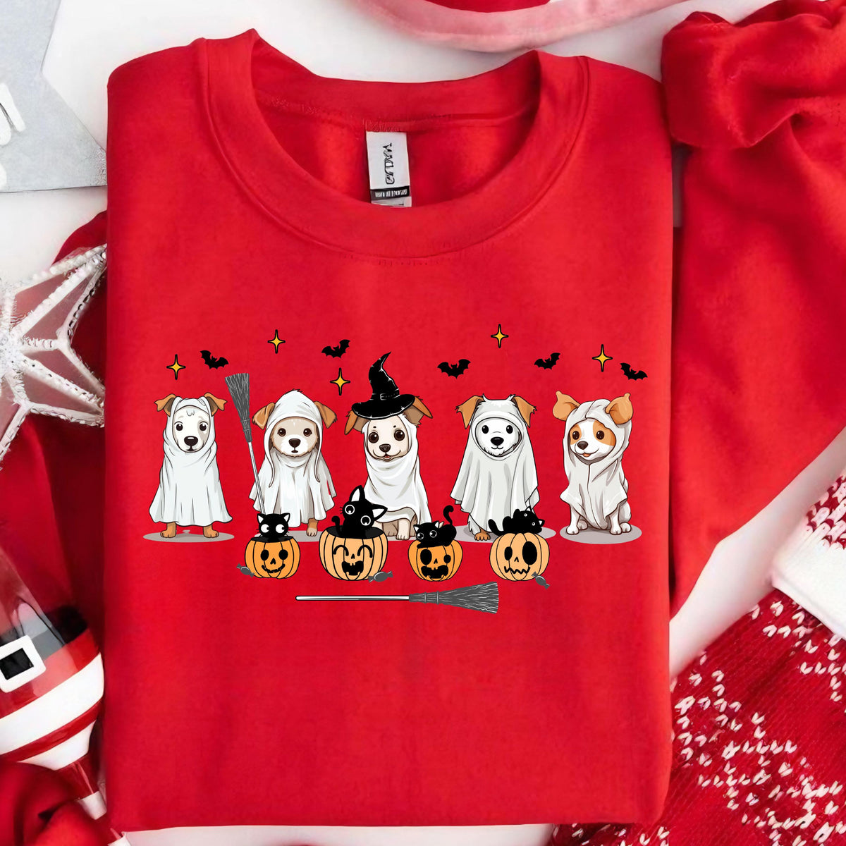 May include: Red crewneck sweatshirt featuring a Halloween-themed design. The graphic includes six dogs dressed in costumes, including ghosts and a witch. Pumpkins, bats, stars, and a broom complete the festive scene.
