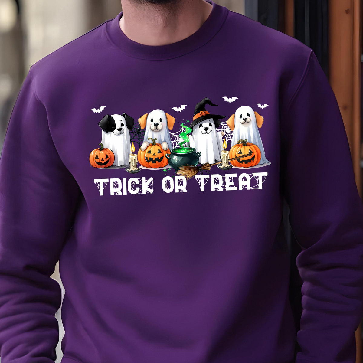 May include: A purple sweatshirt featuring a Halloween-themed graphic. The graphic includes four dogs dressed as ghosts, pumpkins, bats, candles, and the text "Trick or Treat" in white.