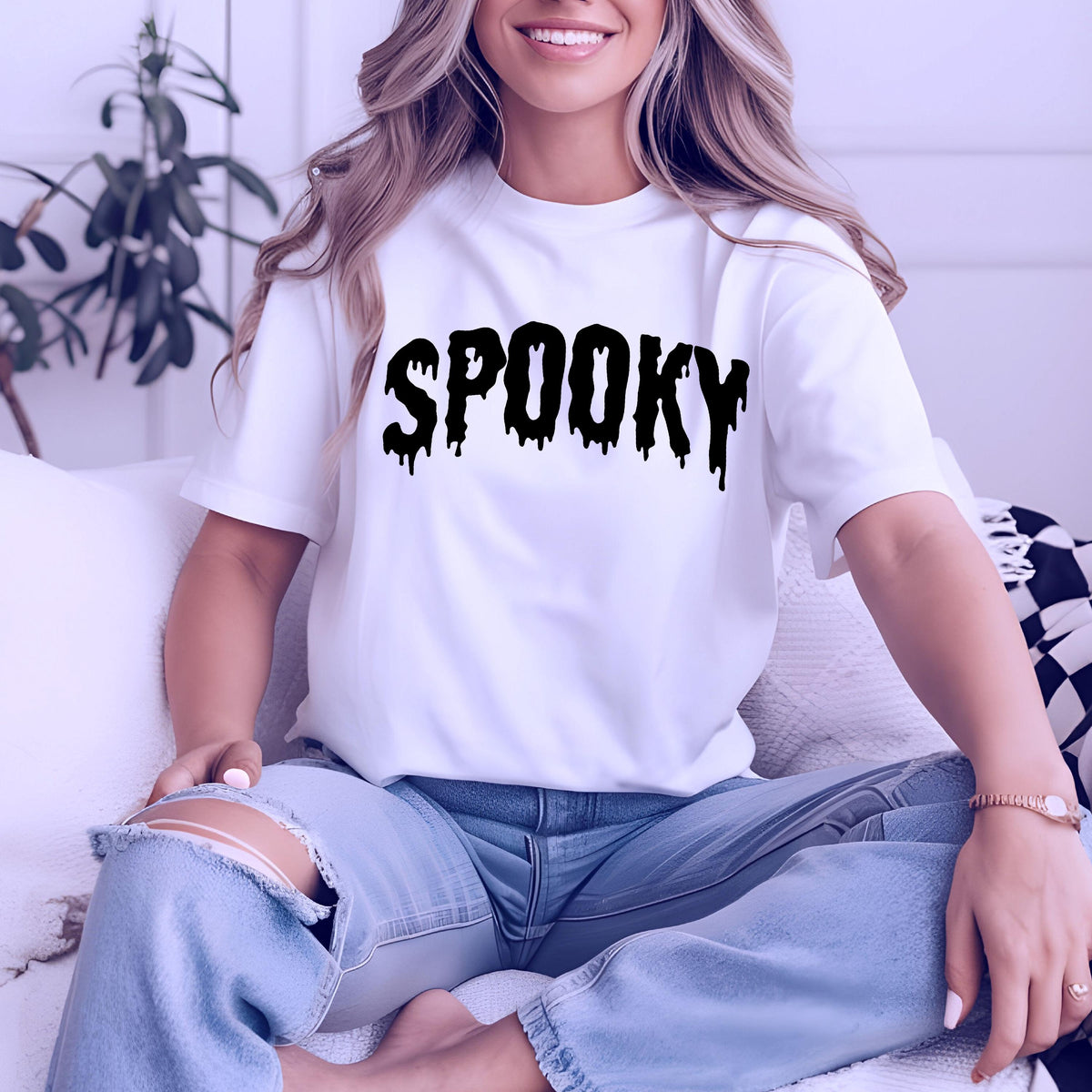 May include: White t-shirt with the word "SPOOKY" in large, dripping black letters. The shirt is short-sleeved and worn with light blue jeans. The overall theme is Halloween.