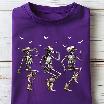May include: A folded purple t-shirt featuring a graphic of three dancing skeletons wearing cowboy hats and boots. White bats are scattered across the top of the shirt. The skeletons are in a line, each in a different dance pose.