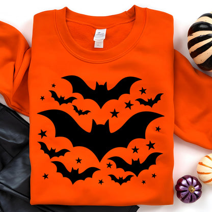 May include: Orange sweatshirt featuring a black bat and star design. The graphic includes several bats of varying sizes and small stars. The sweatshirt is a crew neck style, perfect for Halloween.