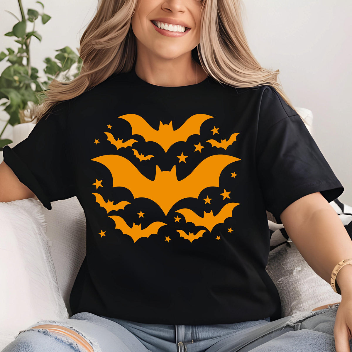 May include: Black t-shirt featuring a Halloween design. The design includes orange bats and stars. The bats are in various sizes and orientations, creating a dynamic and festive pattern. The shirt is made of a soft material.