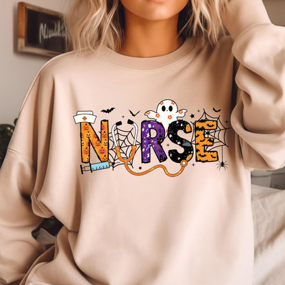 May include: Beige sweatshirt with the word "NURSE" in a Halloween-themed design. The letters are decorated with pumpkins, a ghost, spiderwebs, and a stethoscope. A nurse's hat and syringe are also included in the design.