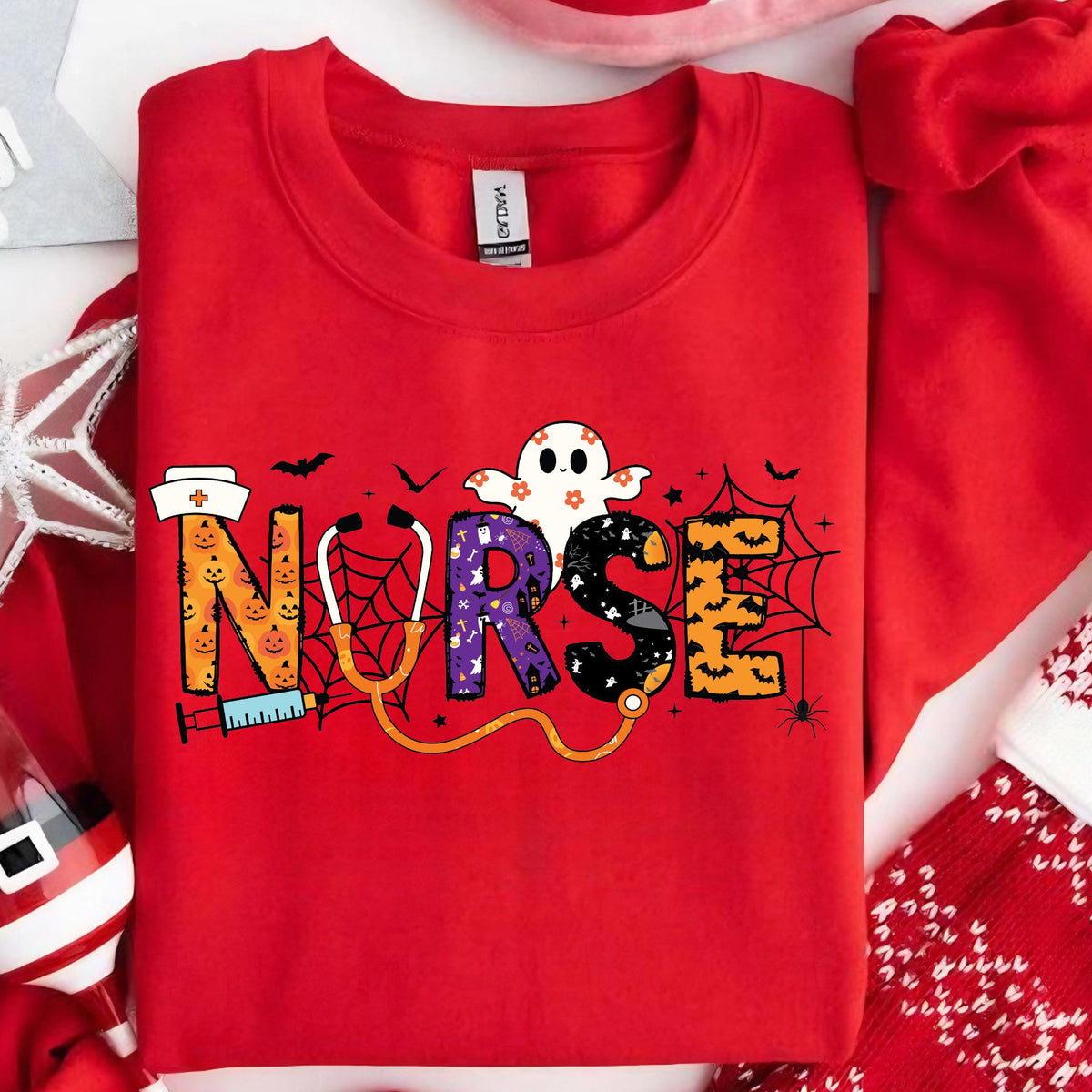 May include: A red sweatshirt with the word "NURSE" in a Halloween-themed design. The letters are decorated with a nurse's hat, a syringe, a stethoscope, spiderwebs, bats, and a ghost. The sweatshirt is made of a soft material.