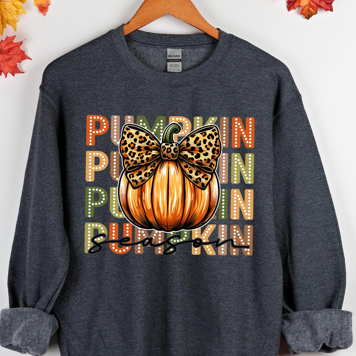 May include: Dark gray sweatshirt with a pumpkin graphic. The pumpkin is orange with a leopard print bow. The words "PUMPKIN SEASON" are printed in orange, green, and white.
