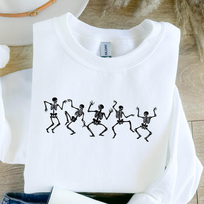 May include: White crew neck sweatshirt with a black graphic of dancing skeletons. The skeletons are in various poses, with arms and legs outstretched. The sweatshirt is made of a soft material and is perfect for Halloween.