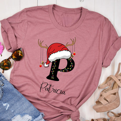 May include: A mauve short-sleeve t-shirt featuring a large black letter P decorated with colorful Christmas lights, topped with a red and white Santa hat and reindeer antlers. The name Patricia is printed in black script below the letter.
