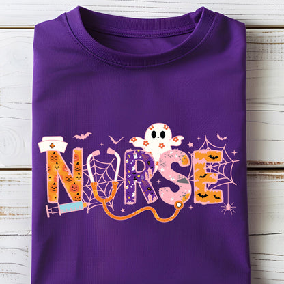 May include: A folded purple t-shirt featuring the word "NURSE" in a Halloween-themed design. The letters are decorated with pumpkins, a ghost, spiderwebs, and bats. A stethoscope graphic is also included.
