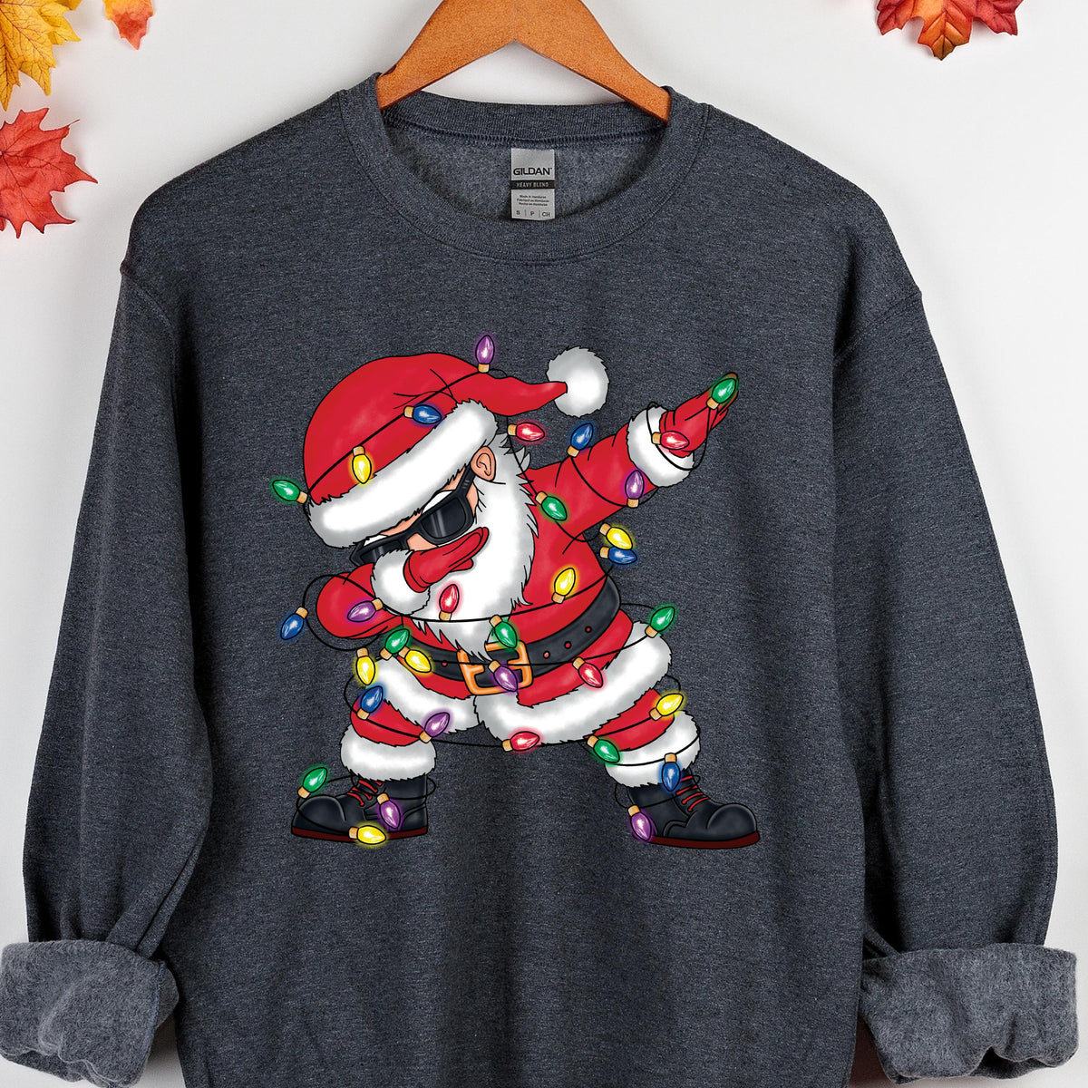May include: A gray sweatshirt with a cartoon image of Santa Claus wearing sunglasses and tangled in Christmas lights. Santa is doing the "dab" dance pose.