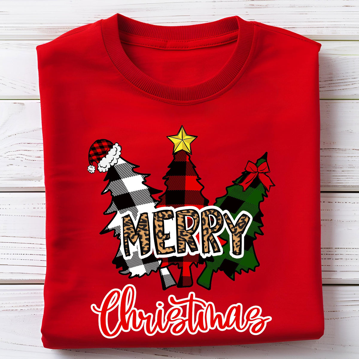 May include: A bright red crew neck t-shirt featuring a graphic of three stylized Christmas trees. The trees have black and white buffalo plaid, red and black plaid, and green and black plaid patterns. The word MERRY is in leopard print.