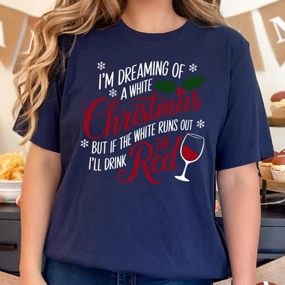 May include: Navy blue t-shirt with the text "I'M DREAMING OF A WHITE Christmas BUT IF THE WHITE RUNS OUT I'LL DRINK THE Red" in white and red. The design includes snowflakes, holly, and a wine glass.