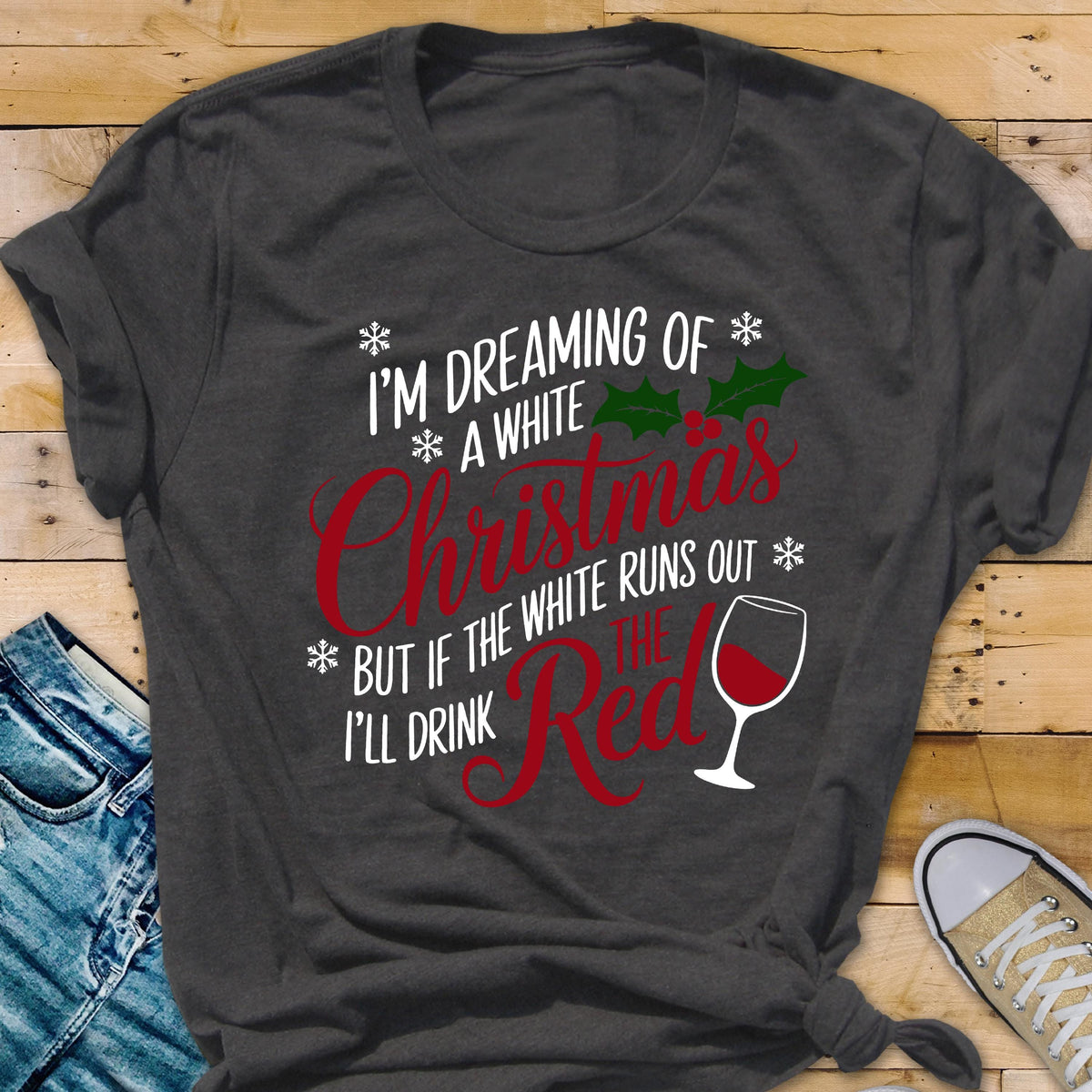 May include: Dark gray t-shirt with the text "I'M DREAMING OF A WHITE Christmas BUT IF THE WHITE RUNS OUT I'LL DRINK THE RED" in white and red. The design includes a wine glass and holly accents.