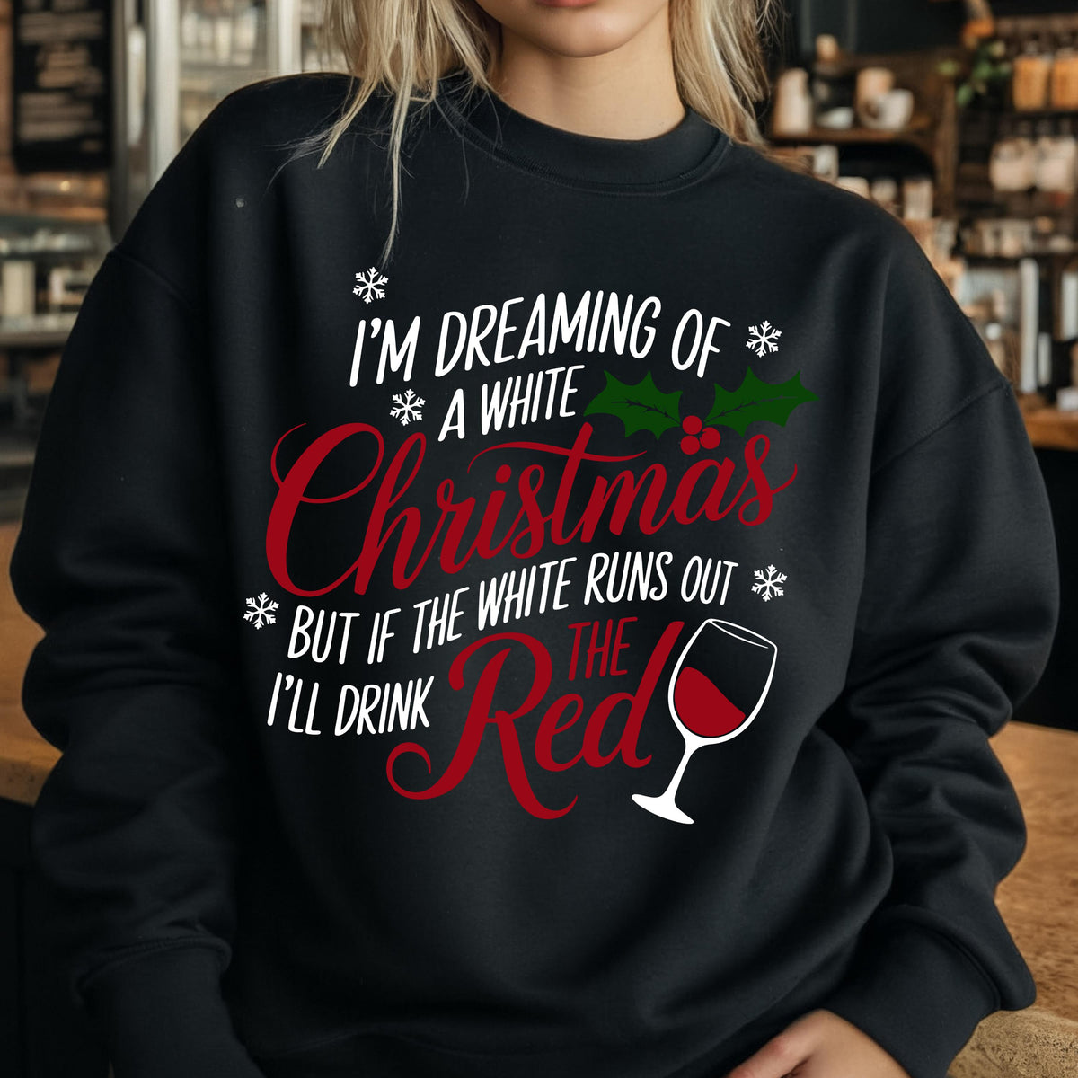 May include: A black long-sleeve sweatshirt featuring white and red text that reads I'M DREAMING OF A WHITE CHRISTMAS BUT IF THE WHITE RUNS OUT I'LL DRINK THE RED. The design includes white snowflakes, green holly leaves with red berries, and a wine glass.