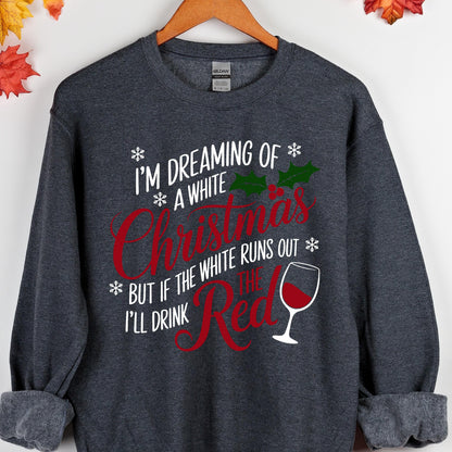 May include: A dark heather gray crewneck sweatshirt featuring white and red text that reads I'M DREAMING OF A WHITE CHRISTMAS BUT IF THE WHITE RUNS OUT I'LL DRINK THE RED. The design includes green holly leaves, red berries, snowflakes, and a wine glass.